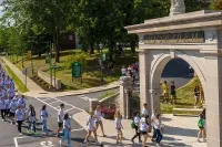 反波胆平台的学生走在拱门上，这是迎新会的传统. 作为当地排名最高的大学 