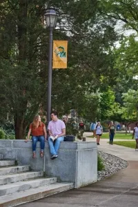 两个学生坐在步行者旗杆附近的文科台阶上，高等教育硕士项目名列前茅